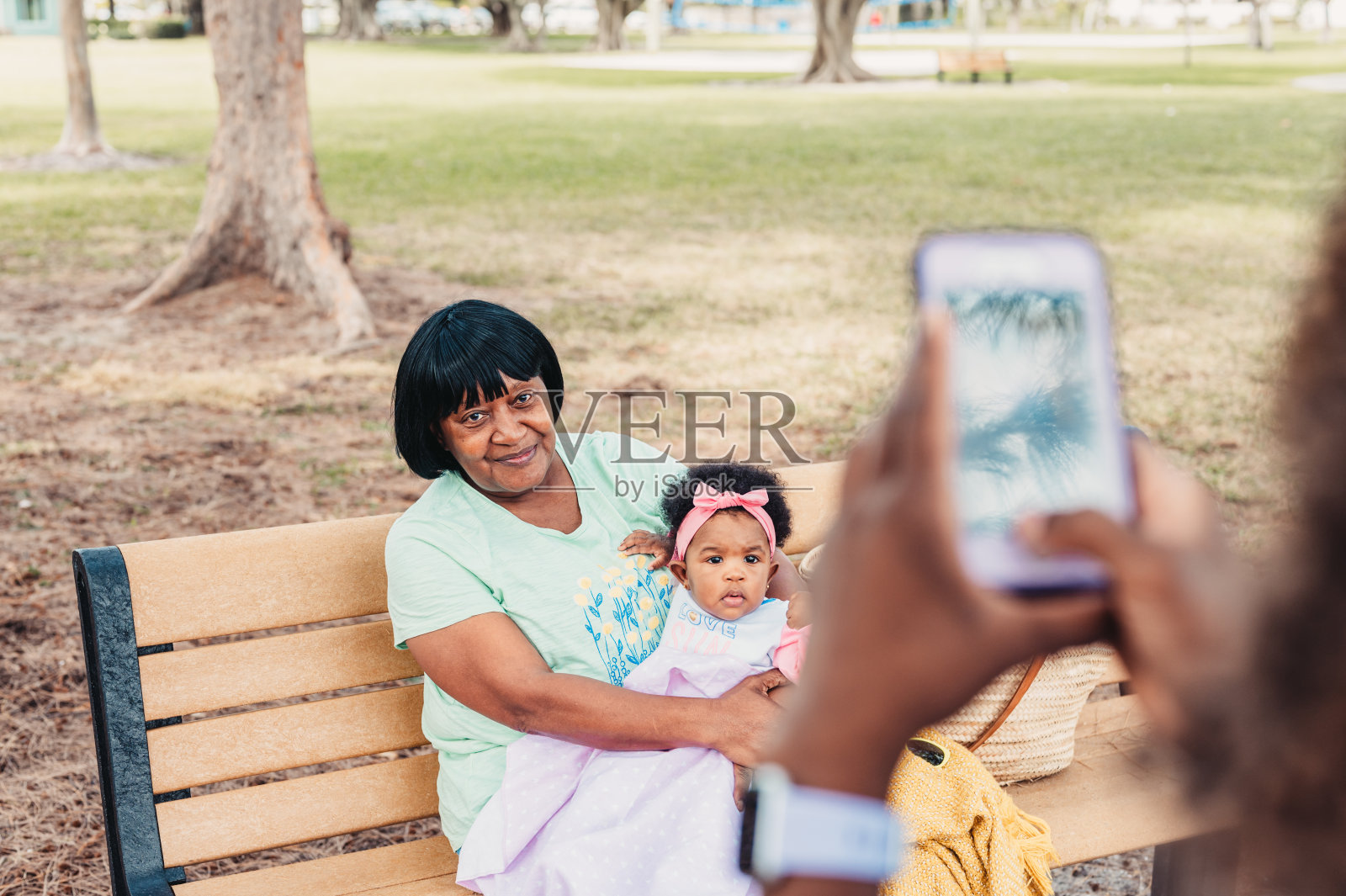 宝宝和奶奶坐在公园的长椅上，第一人称视角在拍照照片摄影图片