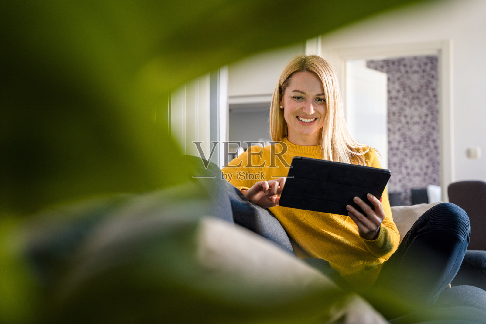 白人中年妇女使用数字平板电脑和有视频电话在家里的沙发照片摄影图片