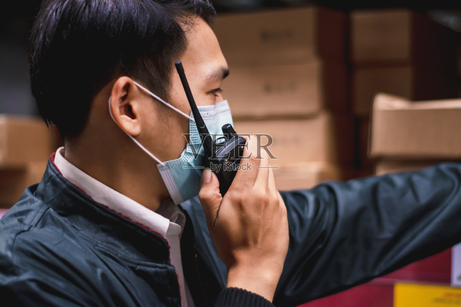 软焦点亚洲工程师或技术员戴口罩，安全安全帽，采用无线电通讯检查商品库存，安全货物管理，仓库，工业企业物流和出口概念照片摄影图片
