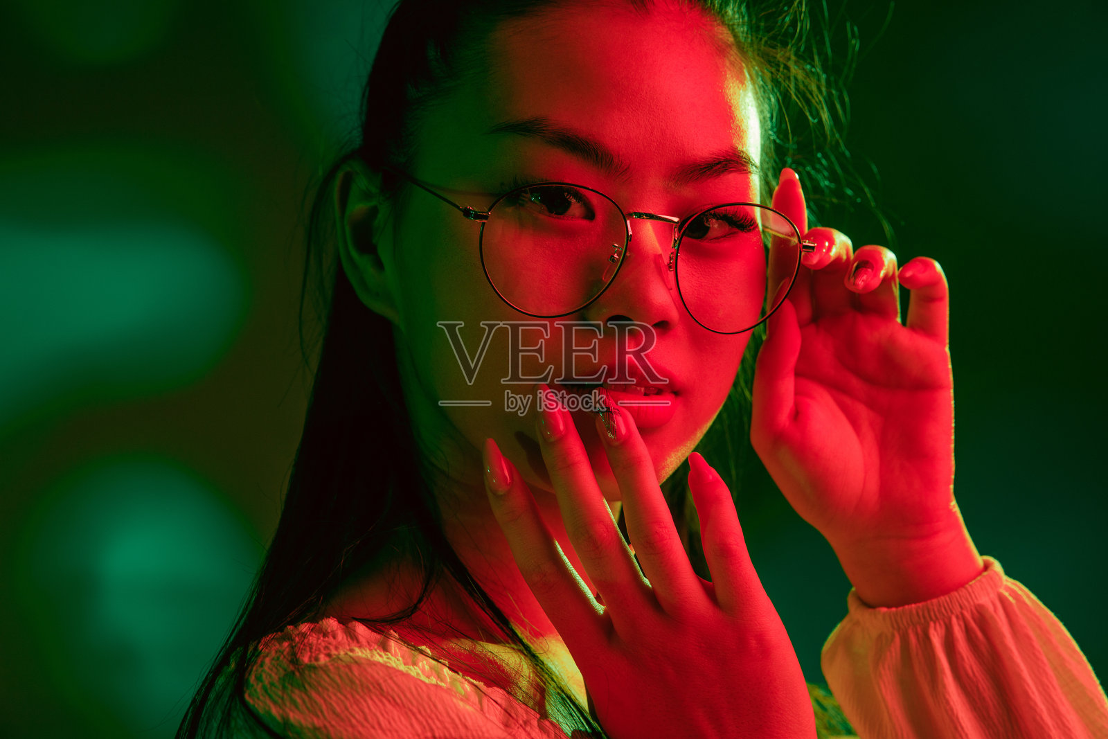 年轻美丽的亚洲女孩孤立在红绿色霓虹灯的背景。照片摄影图片