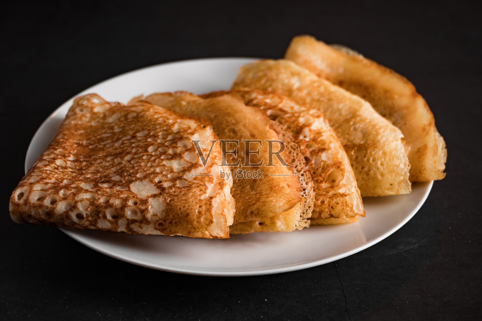 美味的可丽饼放在盘子上，以黑色为背景。传统的俄罗斯食品。放置你的文本。照片摄影图片