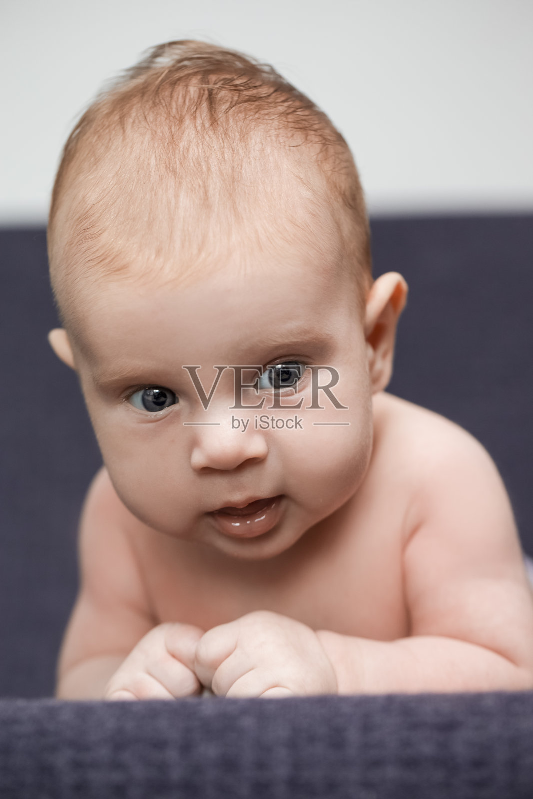 微笑的新生儿男孩平静地躺在针织毯子上的特写。垂直的图像照片摄影图片