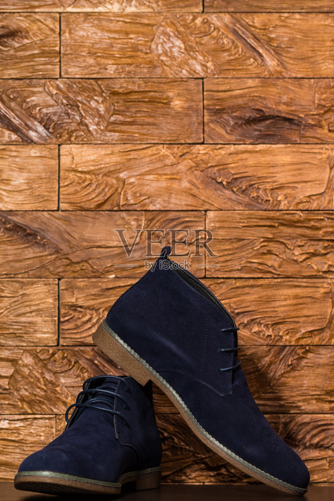 一双男人蓝色麂皮半布洛克靴的特写，反对室内木制背景。垂直的图像组成照片摄影图片