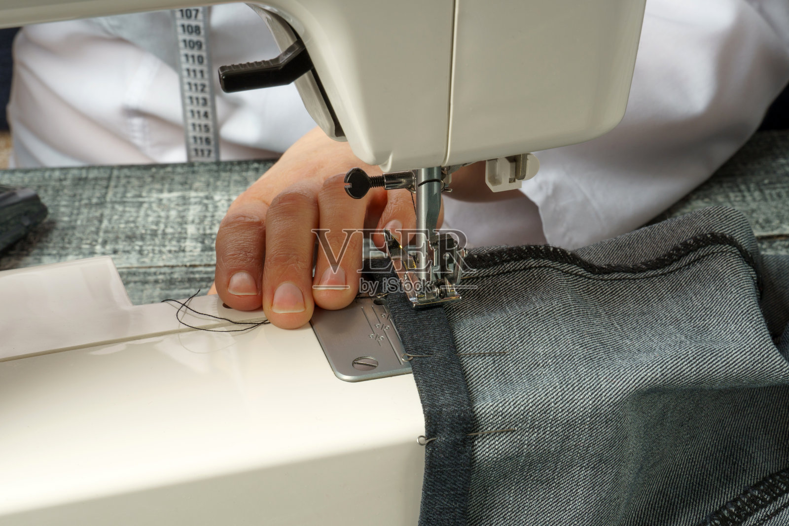 在缝纫机上缩短牛仔裤裤子的过程照片摄影图片