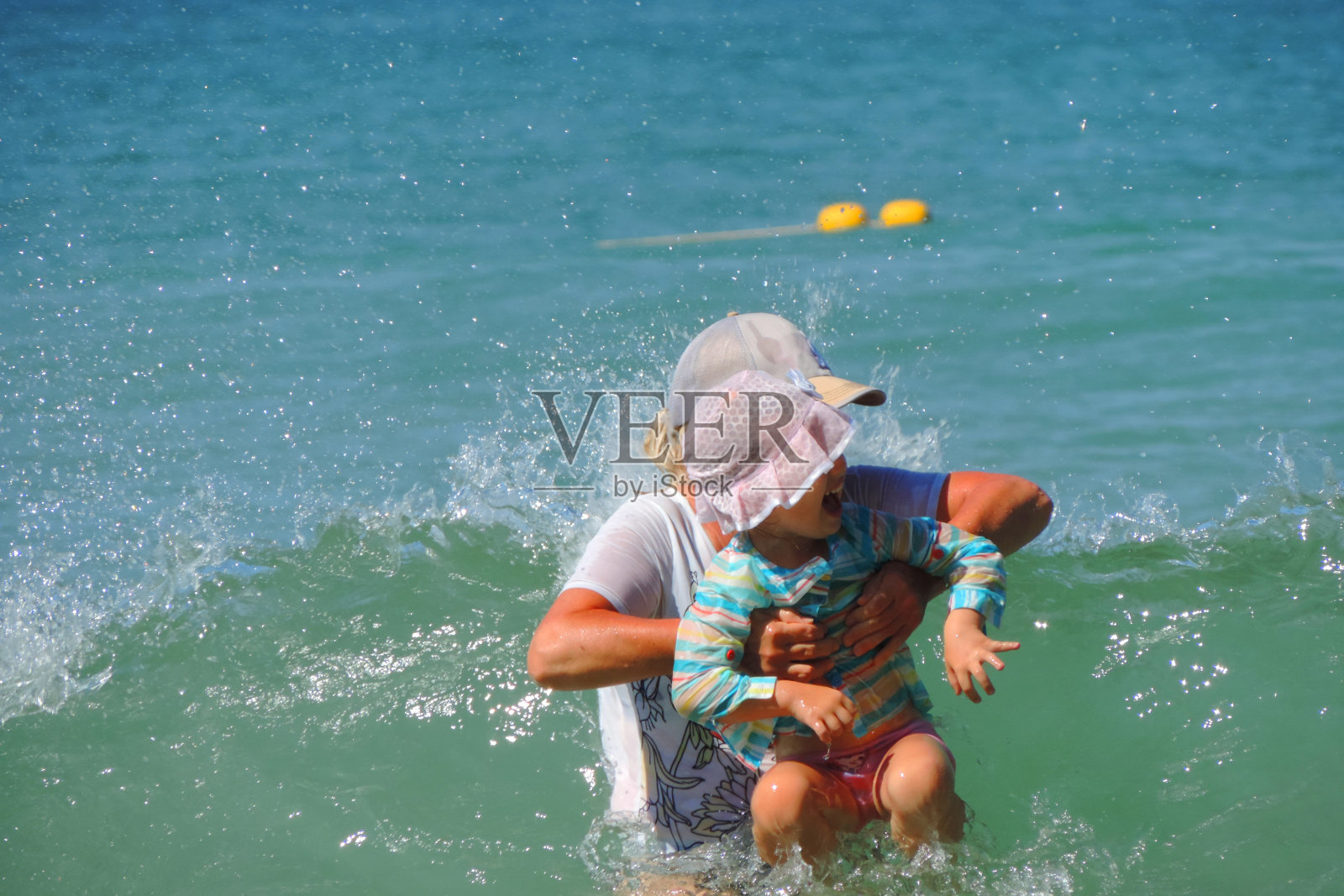 在一个阳光明媚的夏日，妈妈和她可爱的小女儿在海里游泳，享受期待已久的周末。家庭度假概念。照片摄影图片