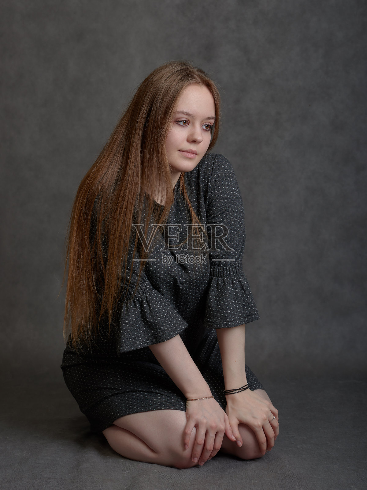 年轻的长发女子坐在她的膝盖上照片摄影图片