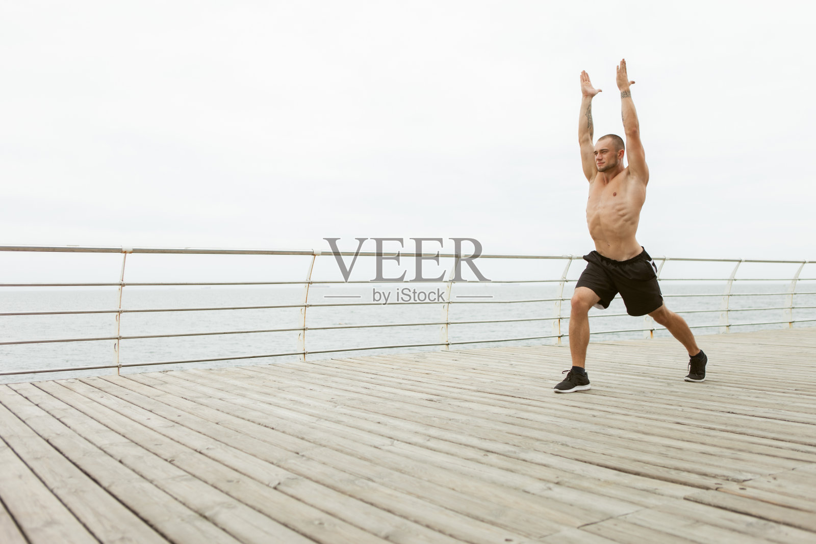 肌肉男练习哈他瑜伽，在海滩上保持平衡。健康的生活方式的概念照片摄影图片
