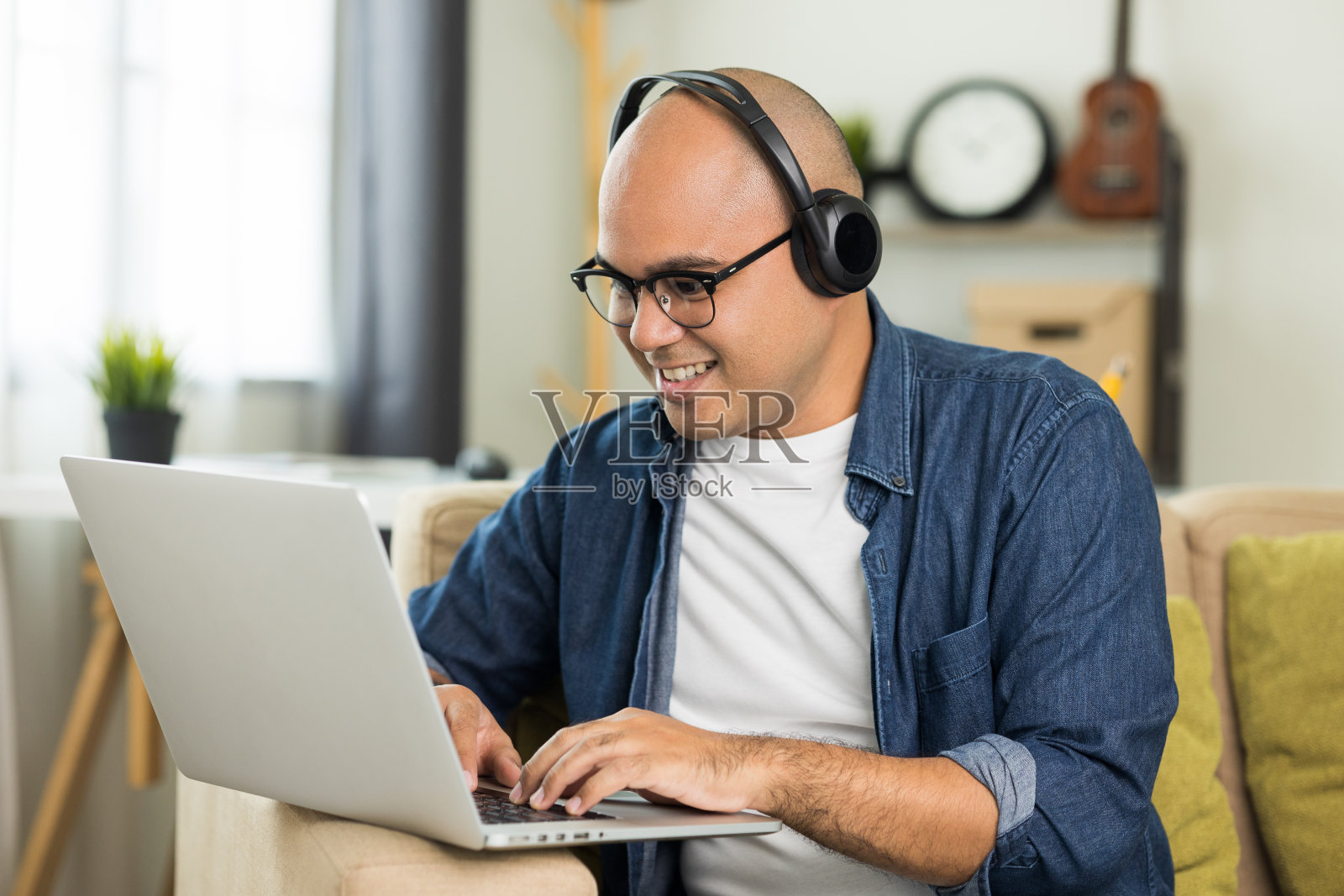 年轻英俊的亚洲男子会议和在线会议保持社交距离与他的业务团队在线聊天或学习在线课程。他戴着耳机。照片摄影图片