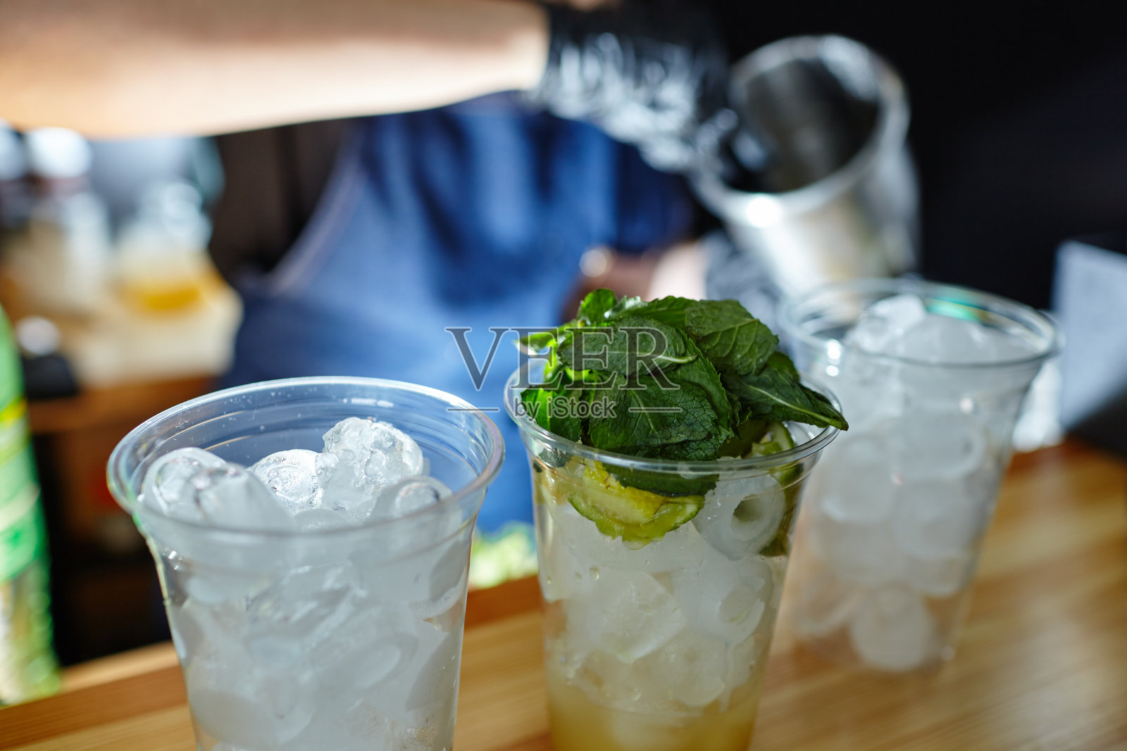 调酒师制作莫吉托鸡尾酒。在酒吧调酒的过程。薄荷叶，冰，酸橙-夜总会饮料的原料照片摄影图片