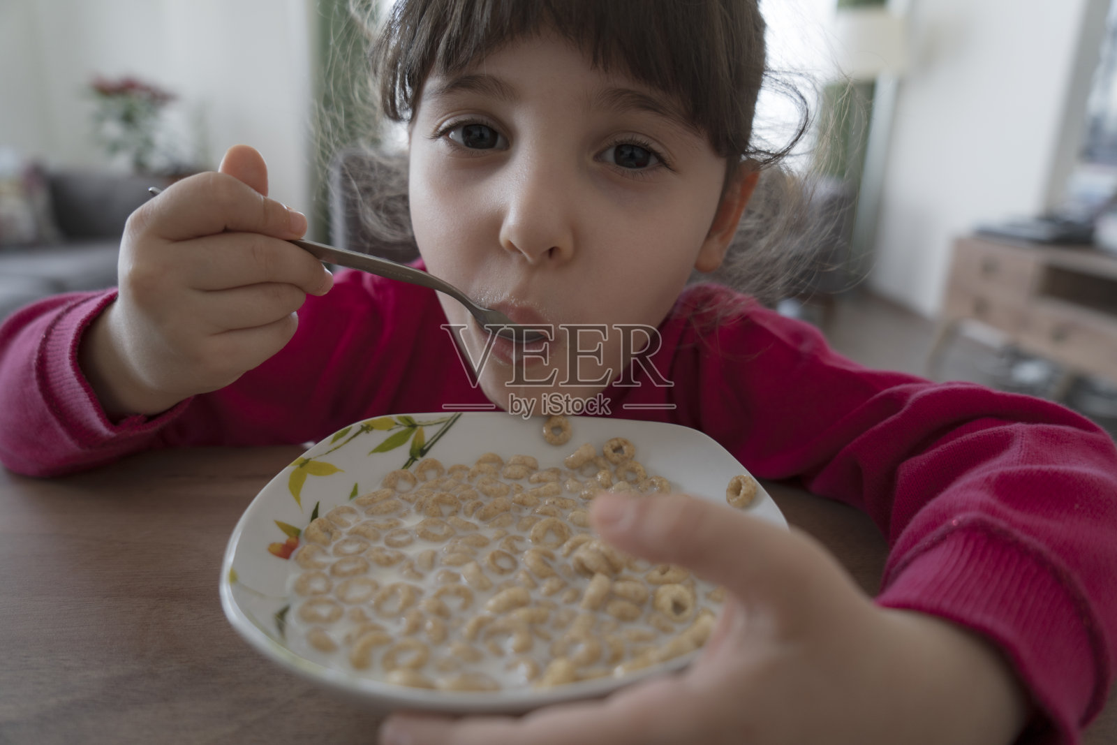 可爱的小女孩早餐吃玉米片和牛奶照片摄影图片