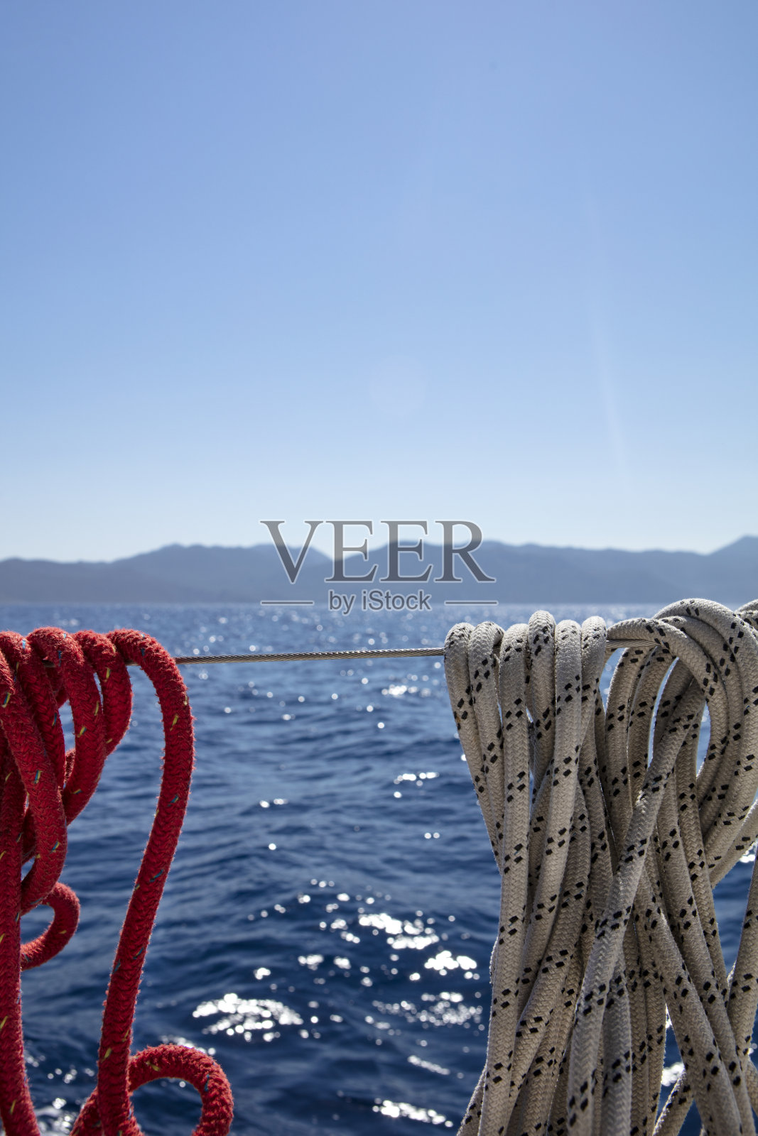近距离的红色和白色的绳子系在船对美丽闪亮的蓝色海洋照片摄影图片
