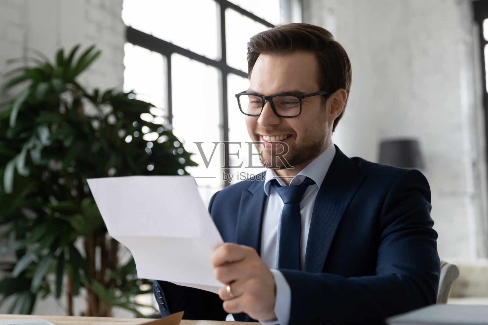 近距离微笑满意的商人戴着眼镜读信照片摄影图片