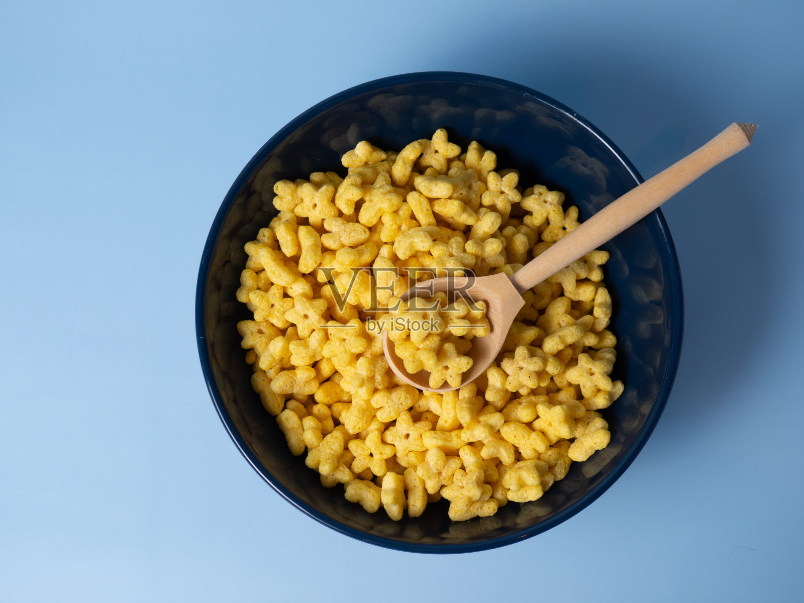 玉米片星号，甜谷物星号在蓝色背景的蓝色碗里照片摄影图片
