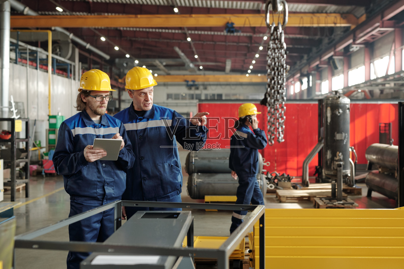 两位工程师站在车间或工厂里讨论新的工业设备照片摄影图片