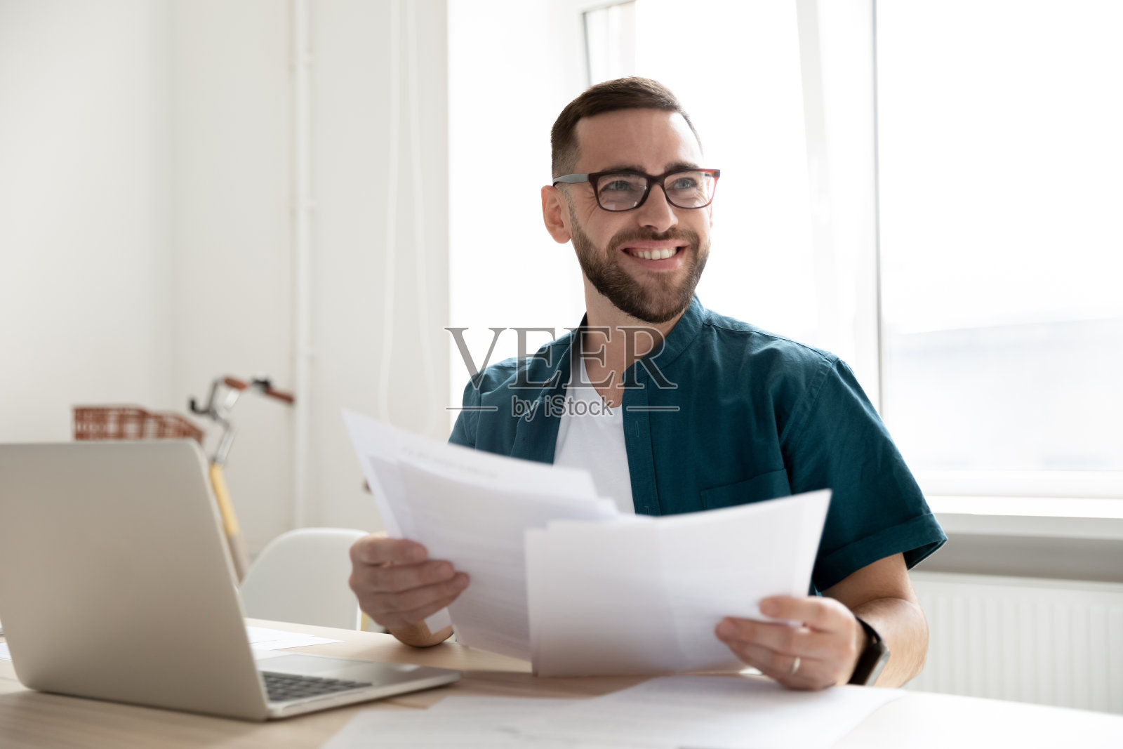 微笑的男员工工作在笔记本电脑上与同事交谈照片摄影图片