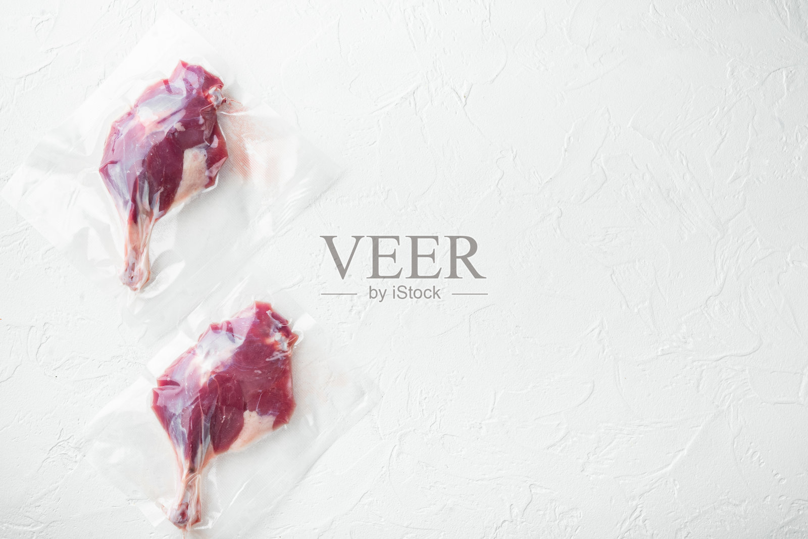 真空包装的生鸭腿，在白色的石头背景，俯视图平lay，与copyspace和文字空间照片摄影图片