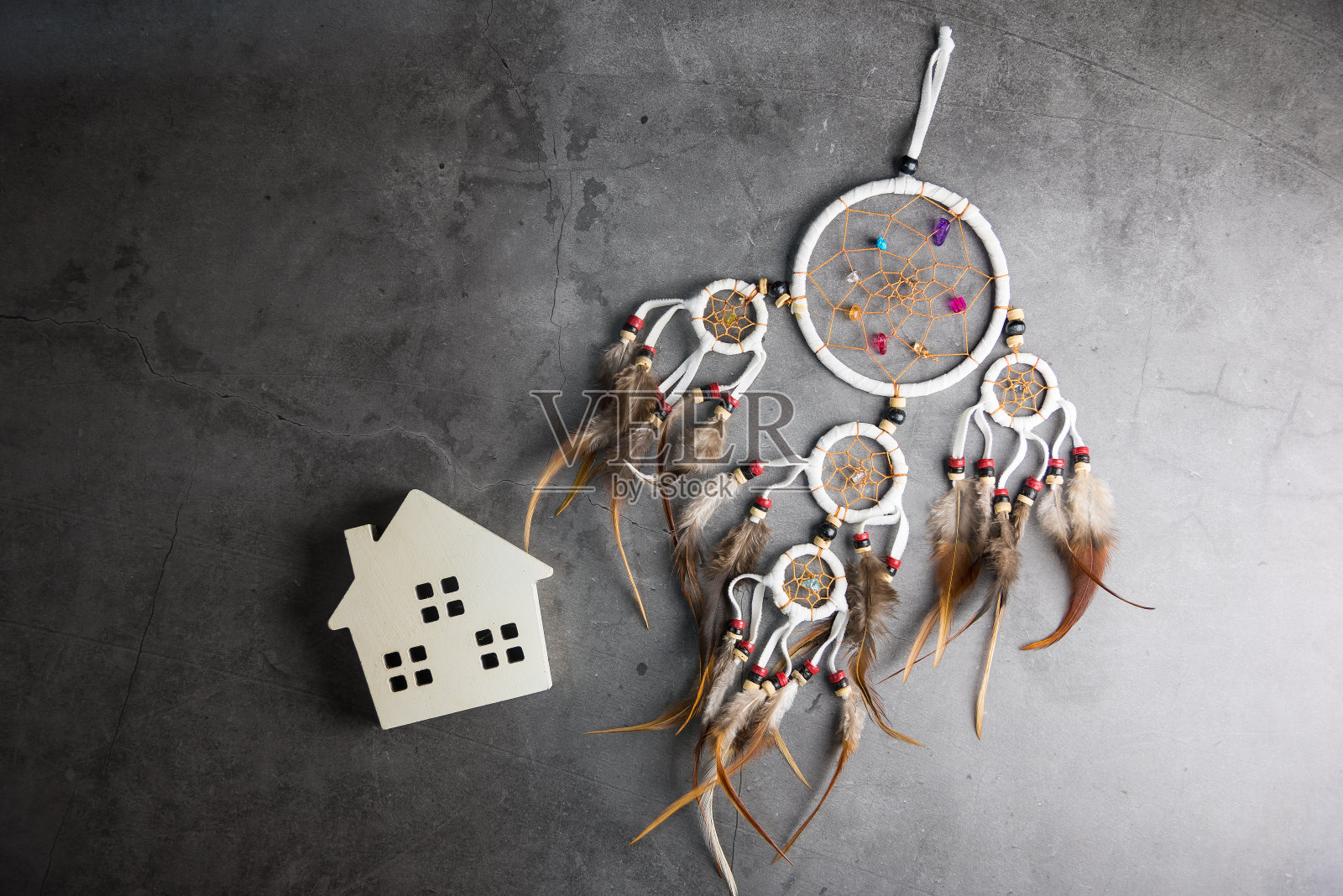 捕梦网和木制房子在灰黑色水泥地板背景与复制空间。保护房子免受邪恶和厄运的概念。照片摄影图片