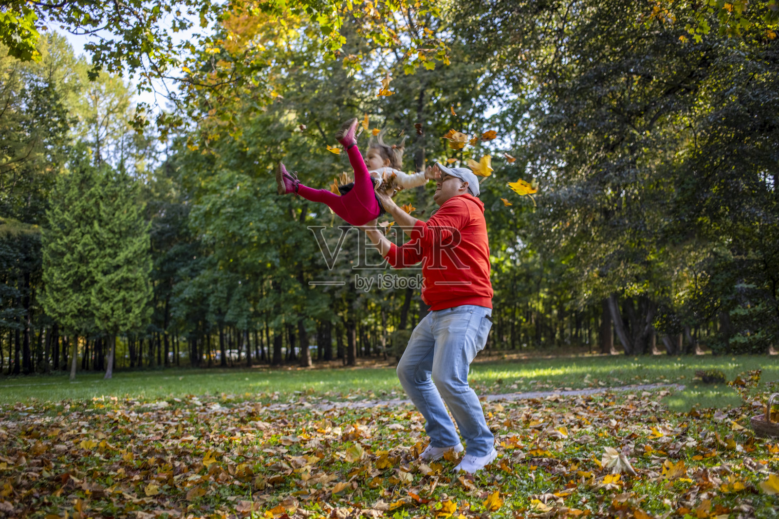 蹒跚学步的小女孩和父亲在户外的秋天公园里玩耍照片摄影图片