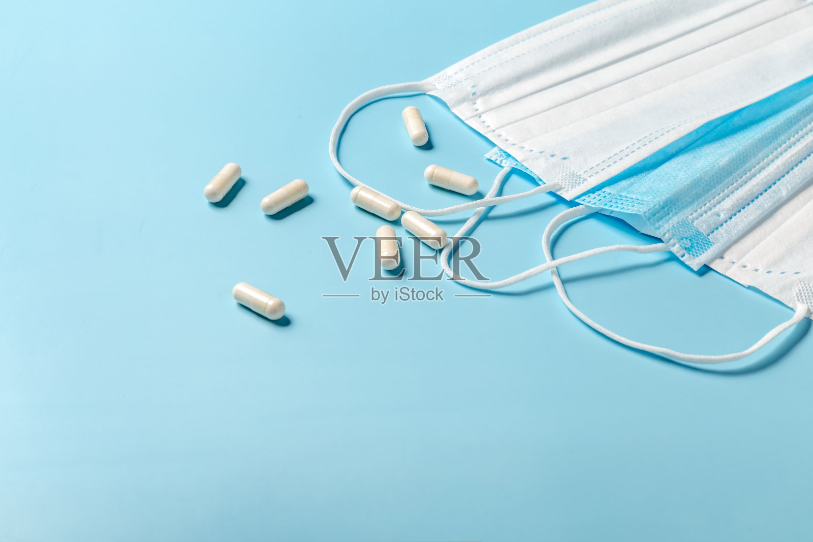 蓝色桌子上的一次性医用口罩和药片。照片摄影图片