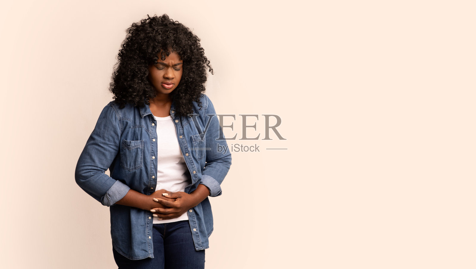 悲伤的黑人女士触摸她的腹部在灰色的背景照片摄影图片