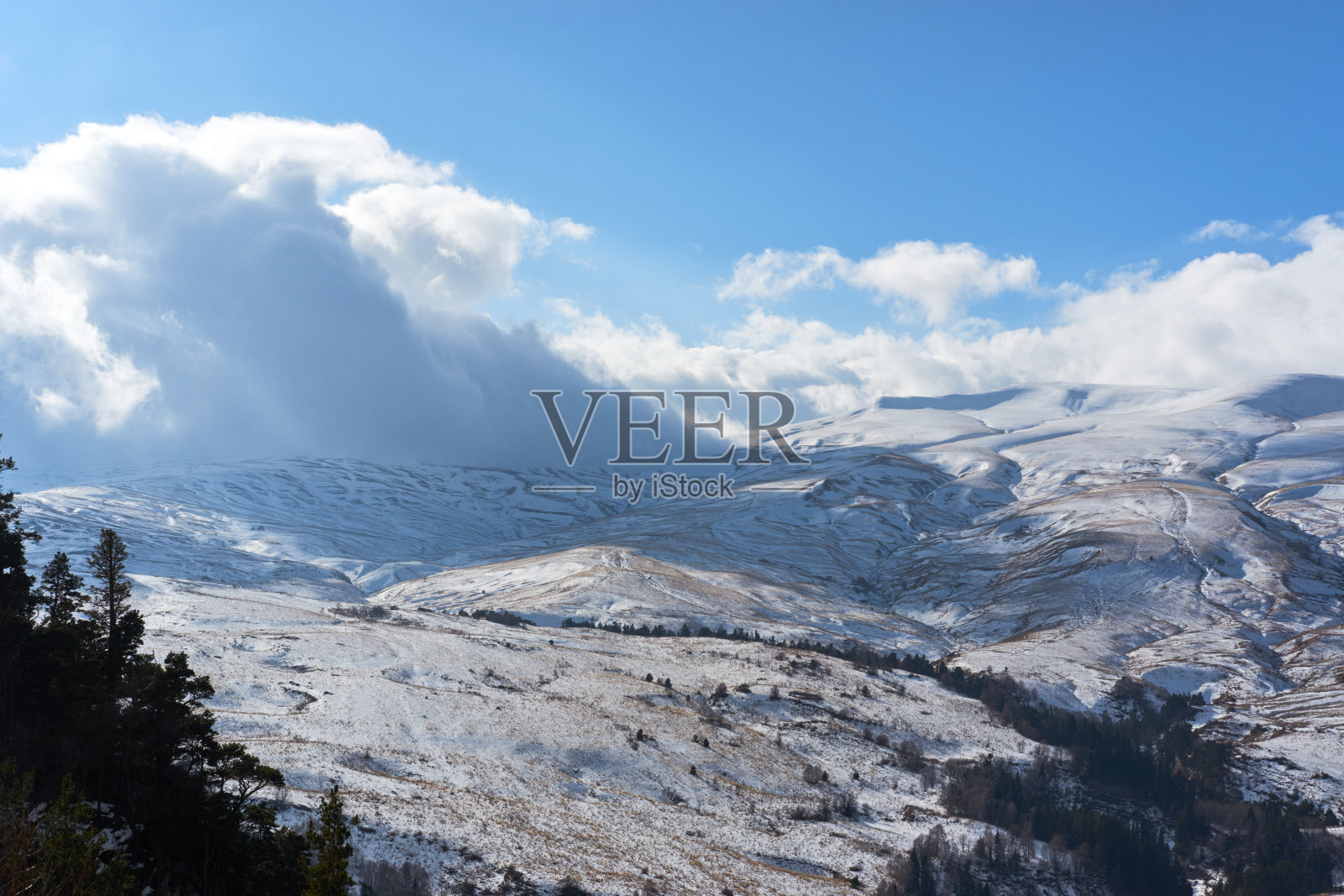 俄罗斯高加索保护区。美丽的风景和自然景观。雪山，暗针叶林绿色森林和低雪白云在晴朗的霜冻的冬季蓝天。照片摄影图片