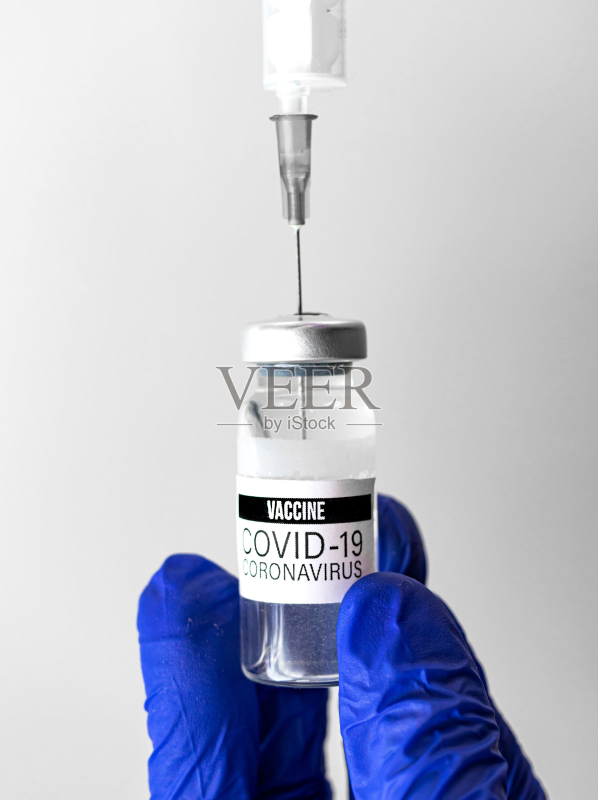 戴蓝手套的医生使用瓶内注射器注射covid-19疫苗照片摄影图片