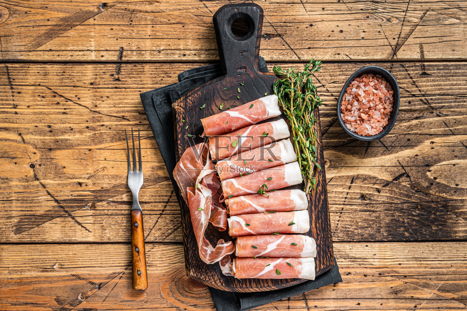 干燥的帕尔马火腿和百里香放在木砧板上。木制背景。俯视图照片摄影图片