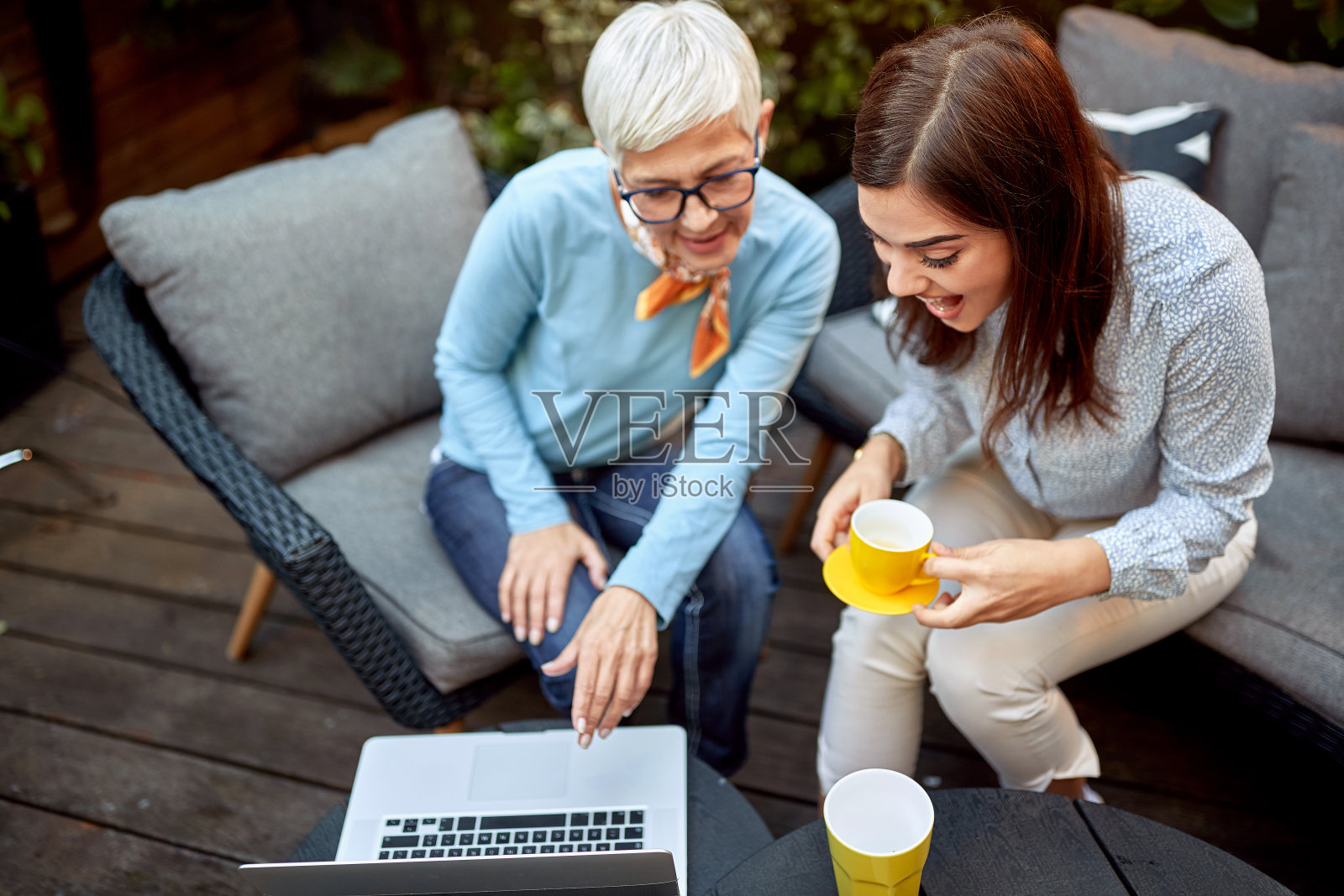 母亲和女儿在看笔记本电脑上的内容，微笑和大笑照片摄影图片