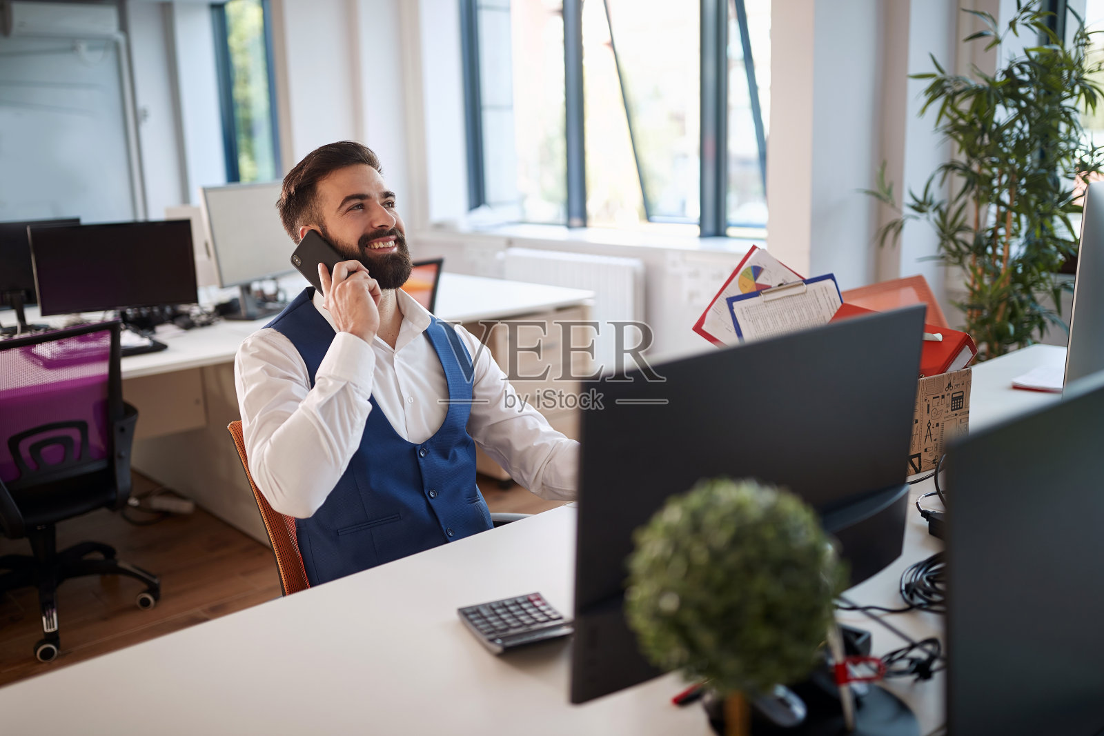 年轻的商人独自在办公室里，讲着电话，接收着好消息。成功，好消息，经营理念照片摄影图片