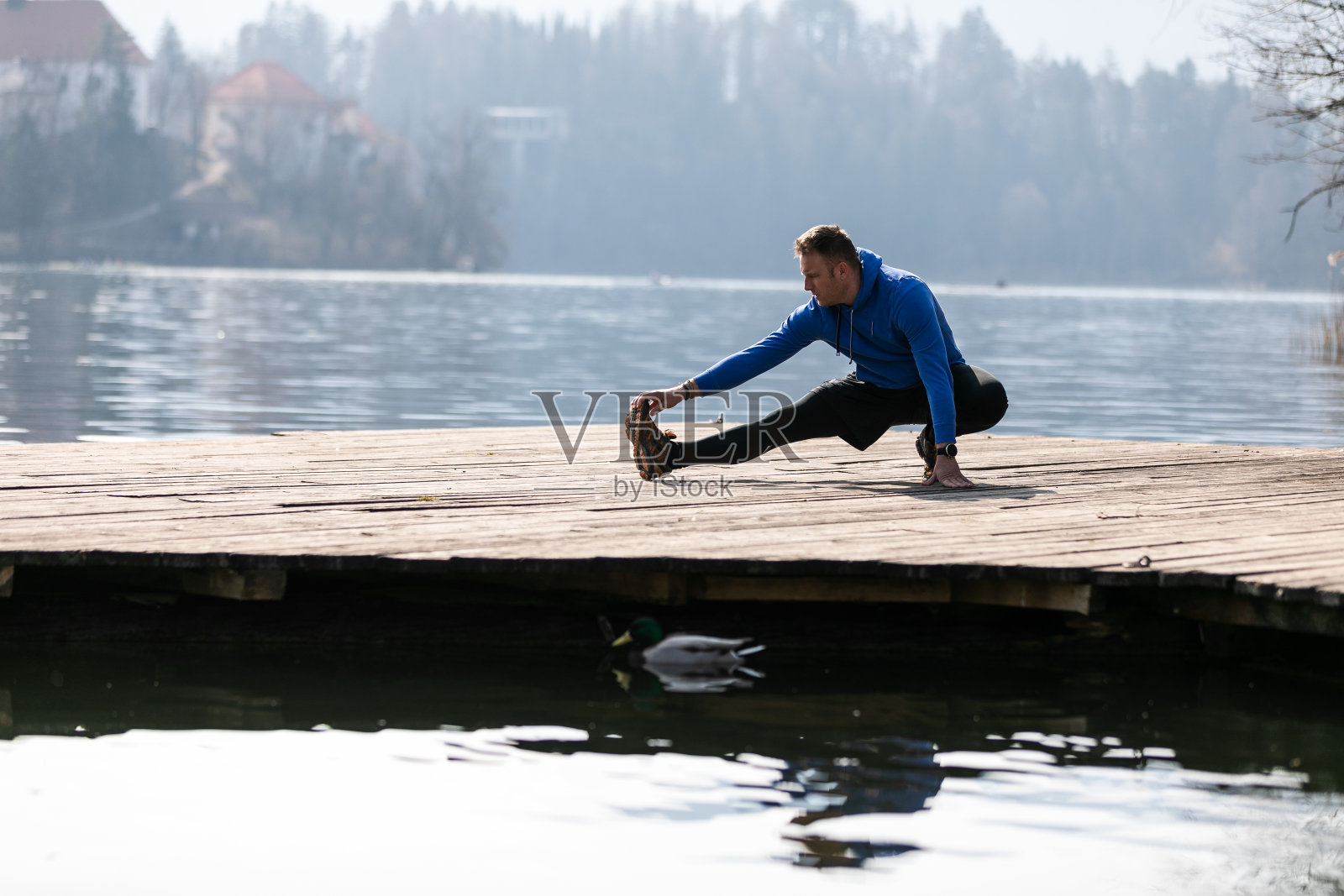 一个人在湖的码头上锻炼照片摄影图片