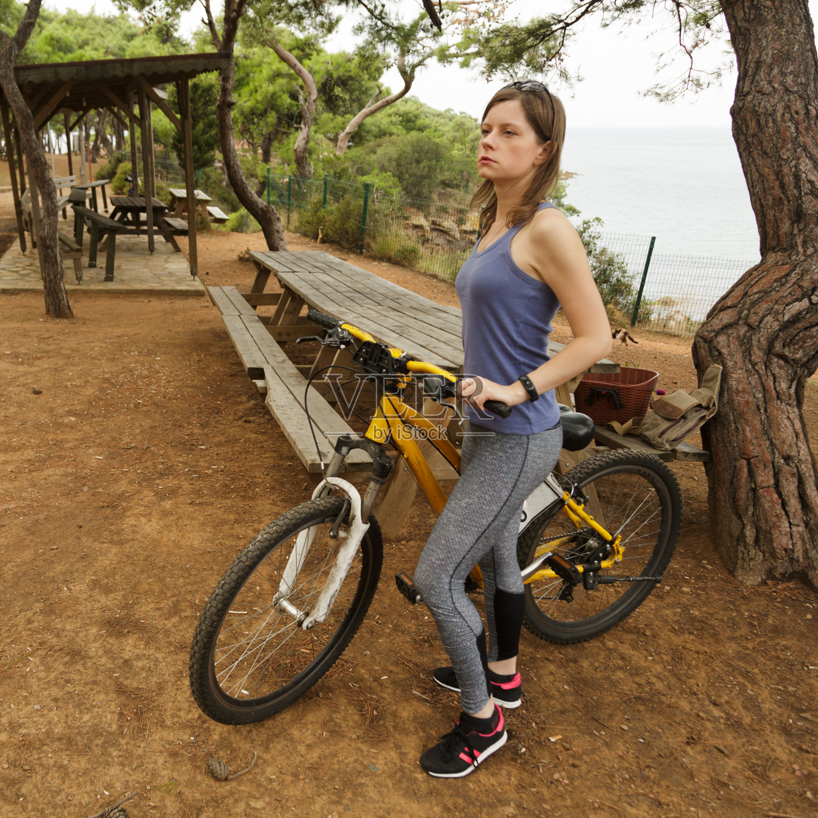 骑自行车的女人在公园里的自行车附近喝水。照片摄影图片