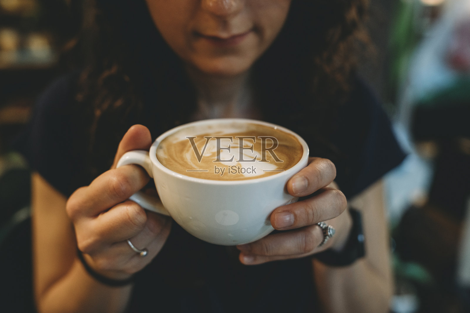 年轻的成年女子在咖啡店喝着卡布奇诺照片摄影图片