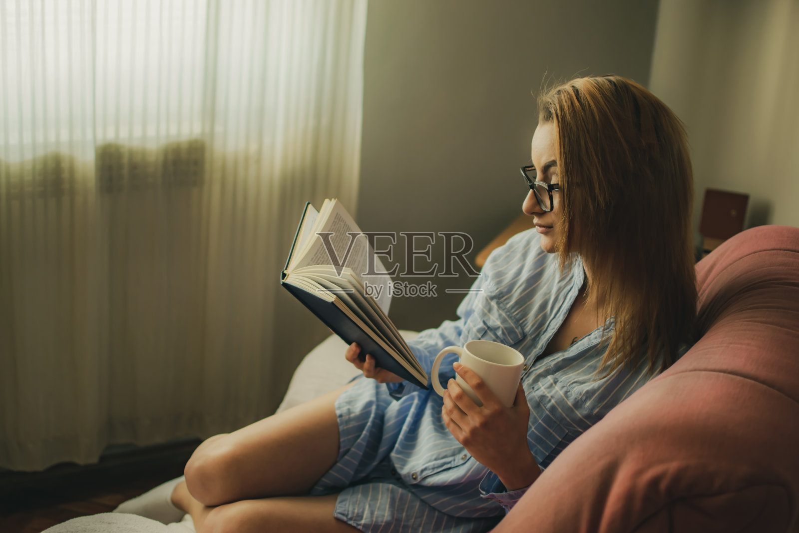 年轻女子喜欢周日下午看书，喝点咖啡或茶。照片摄影图片
