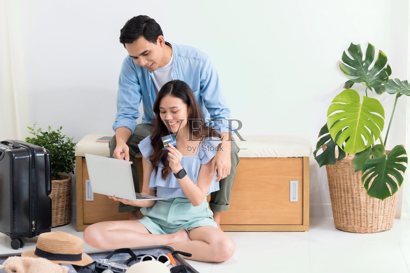 亚洲旅游夫妇计划旅游信息与笔记本电脑和打包手提箱旅行前的旅行日期在家里的背景。新冠肺炎疫情发生后，安全旅游理念。照片摄影图片