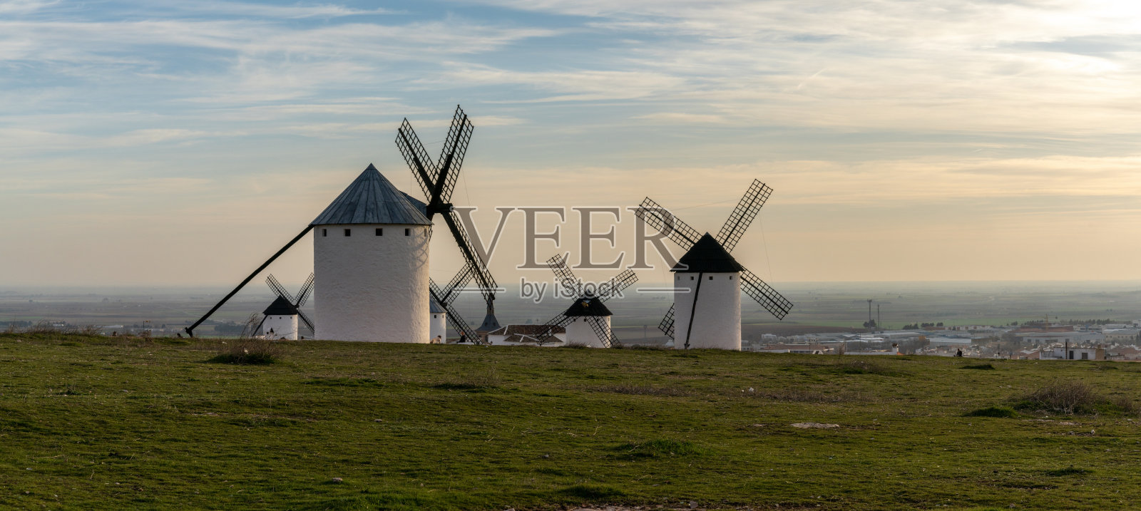 在温暖的夜晚灯光下，拉曼查镇的白色风车照片摄影图片