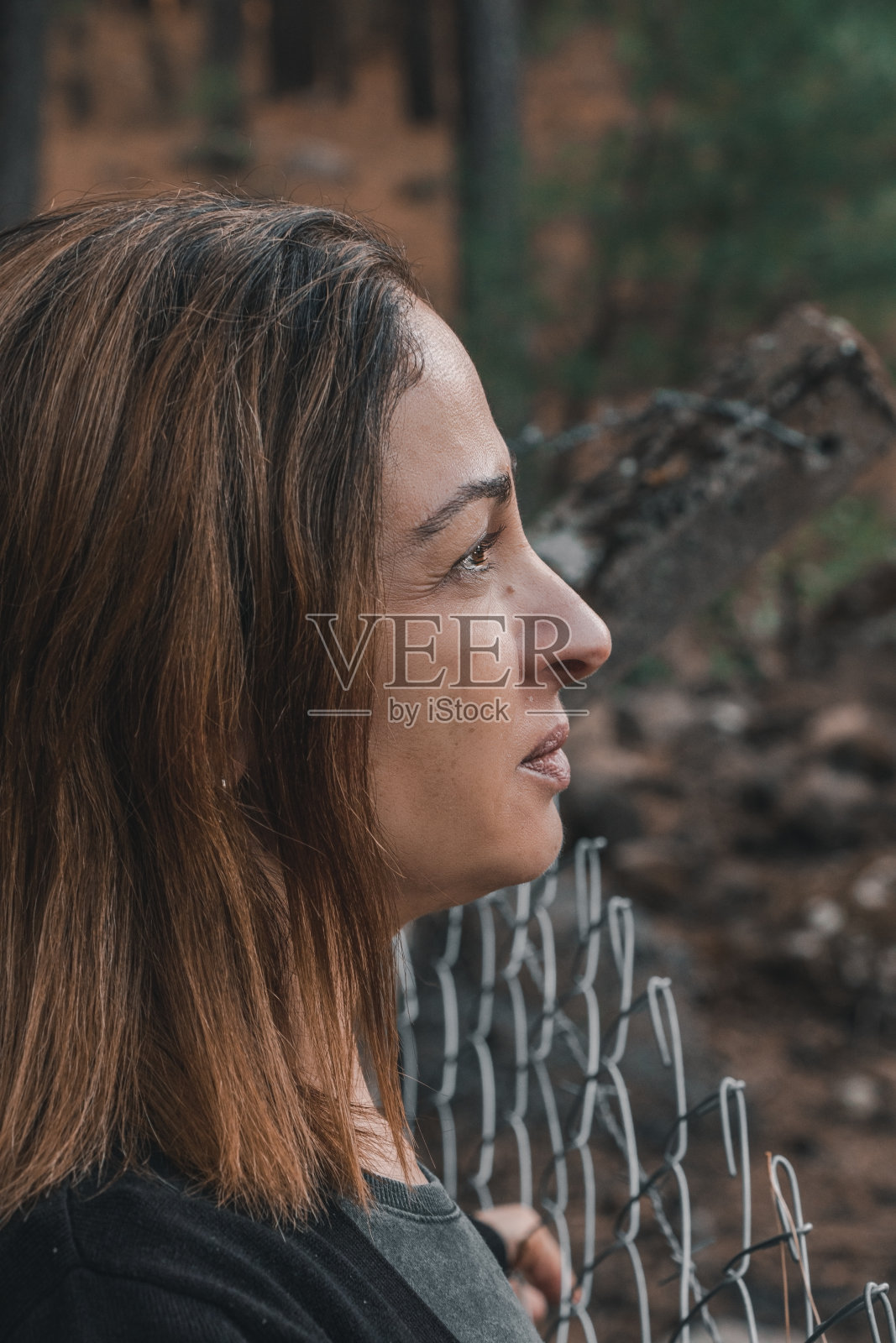 在森林里，一个女人正往后看篱笆照片摄影图片