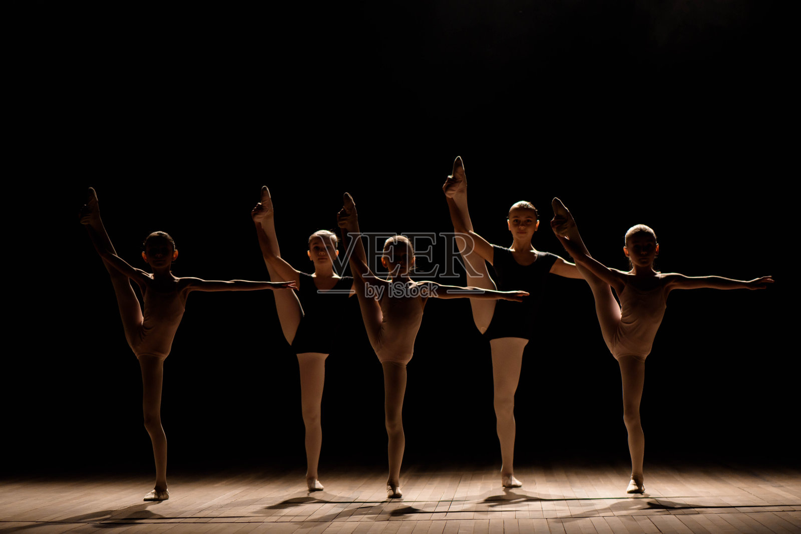 柔韧的芭蕾舞演员在昏暗的灯光下伸展四肢。照片摄影图片