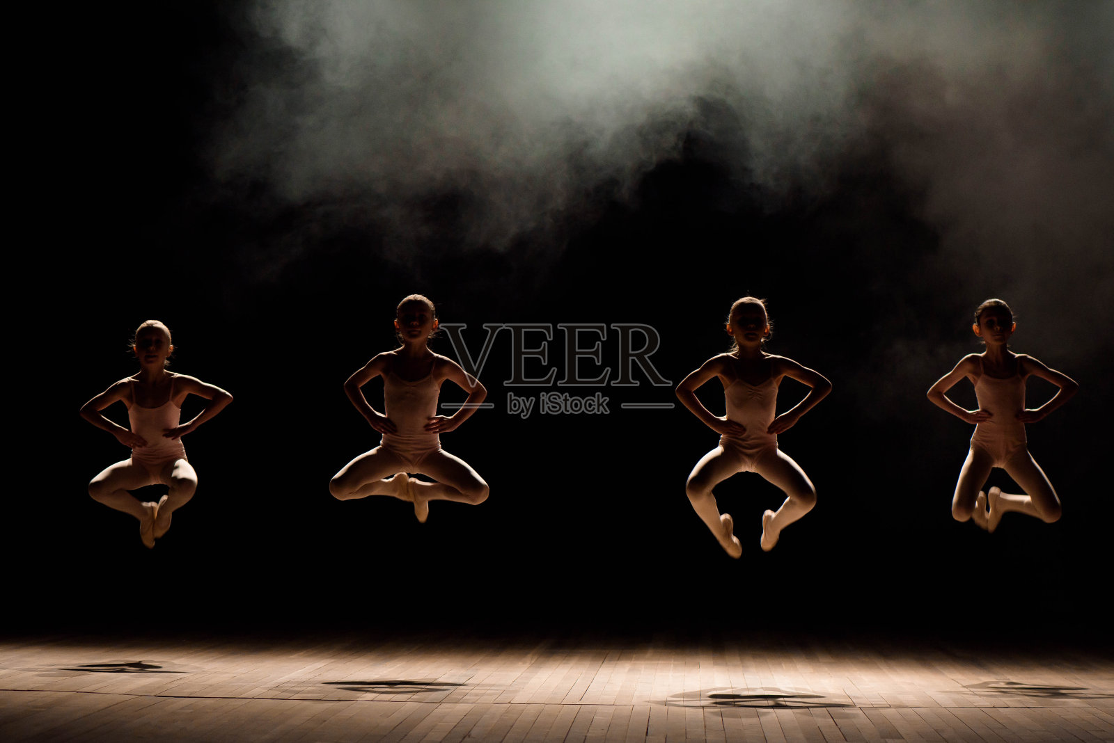 一群小型芭蕾舞者在灯光和烟雾中在舞台上排练照片摄影图片