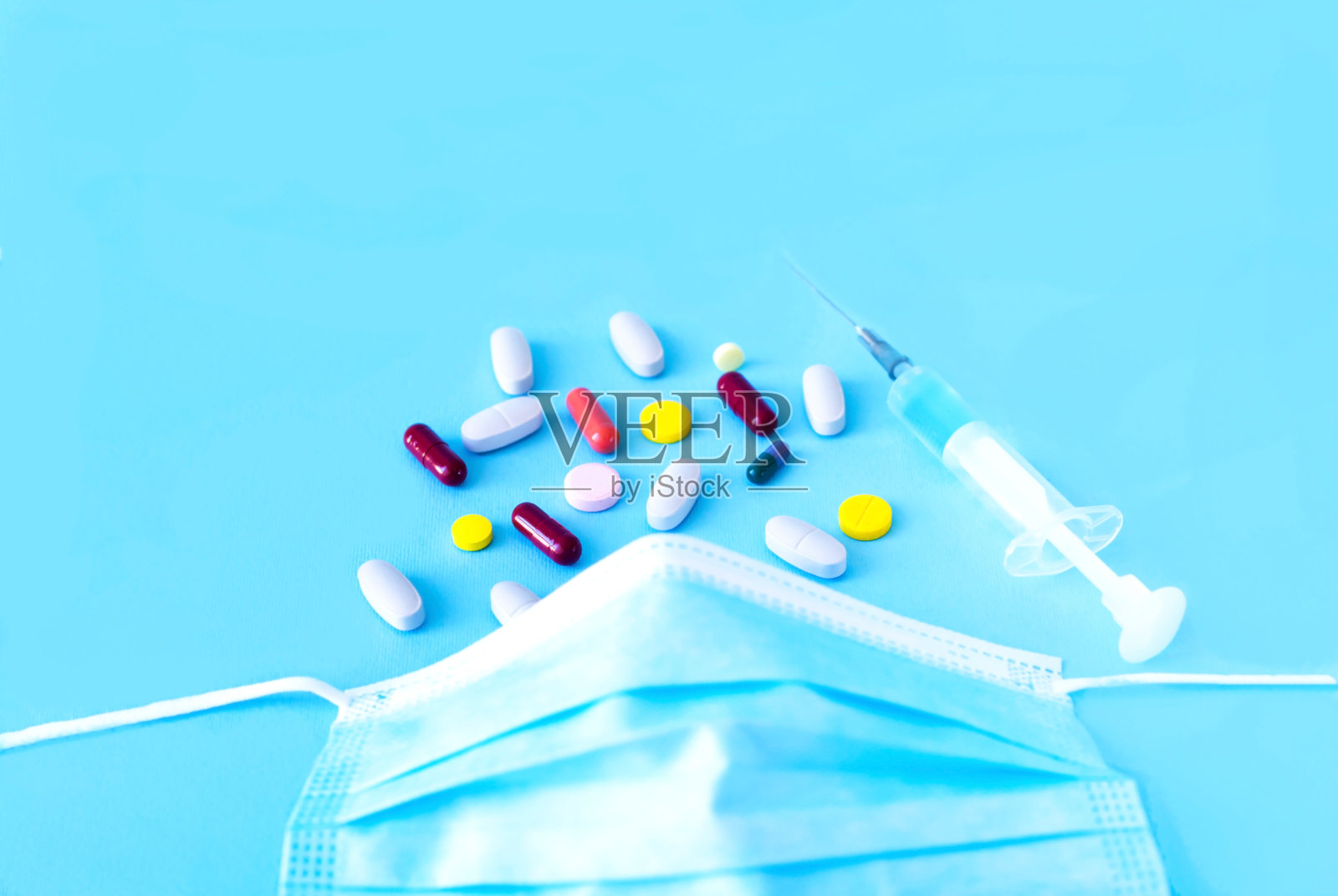 医用防护口罩和蓝色背景上的多种颜色的药物。治疗冠状病毒症状或预防冠状病毒。照片摄影图片