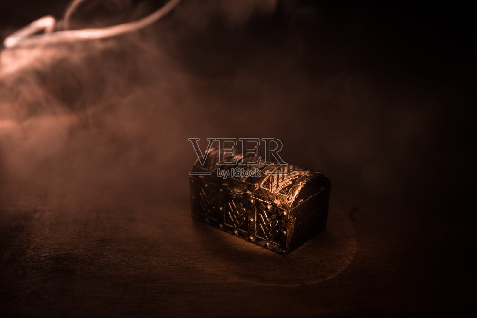 一个黑色的木制宝箱，盖子盖在木桌上。照片摄影图片