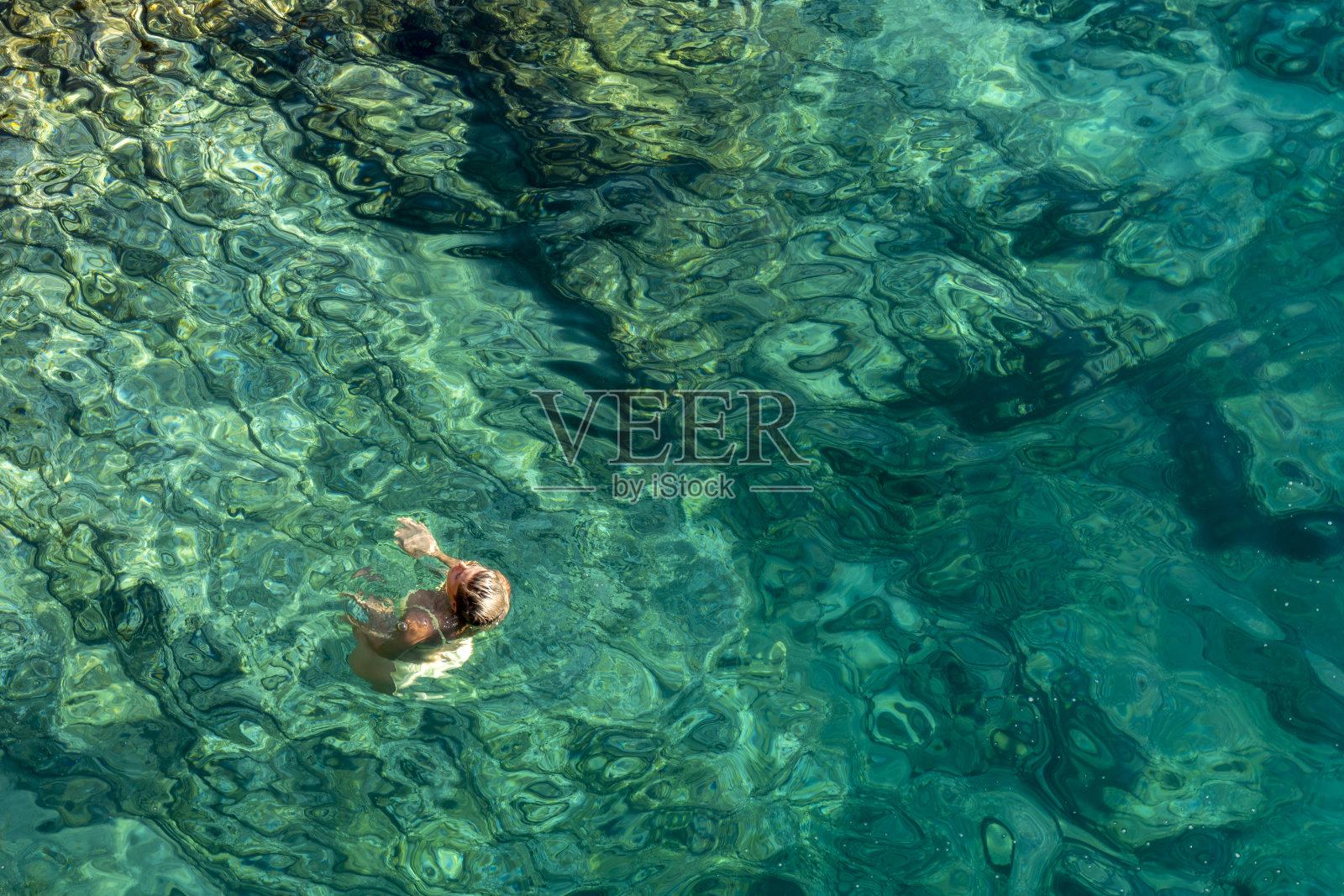 年轻女子在海里游泳。照片摄影图片
