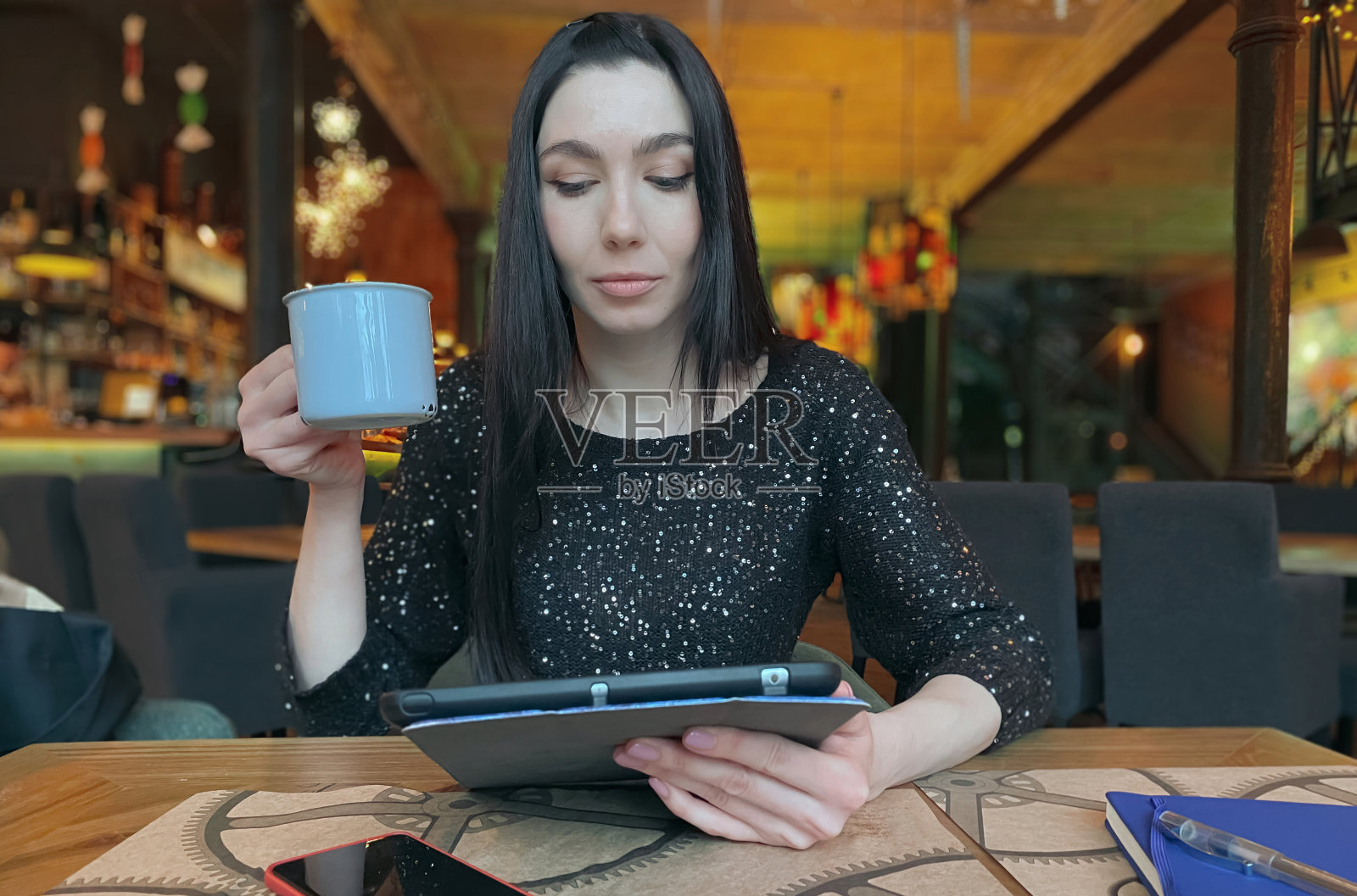 一个棕色头发的女孩在咖啡馆工作，附近有一台平板电脑，一部手机和一个笔记本。共同办公,工作流程组织。经营理念。照片摄影图片