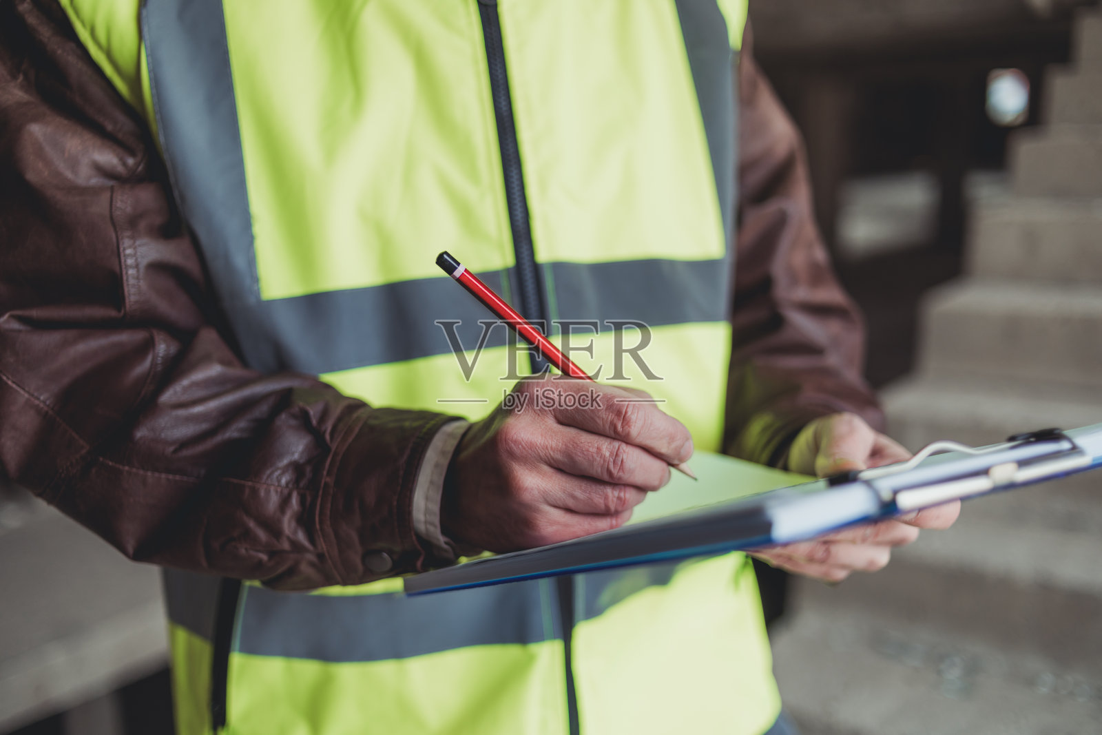 工程师在施工现场阅读平面图的肖像。一位戴着安全帽、穿着安全背心的土木工程师正在使用数码平板电脑。致力于建筑改造和投资评估。照片摄影图片