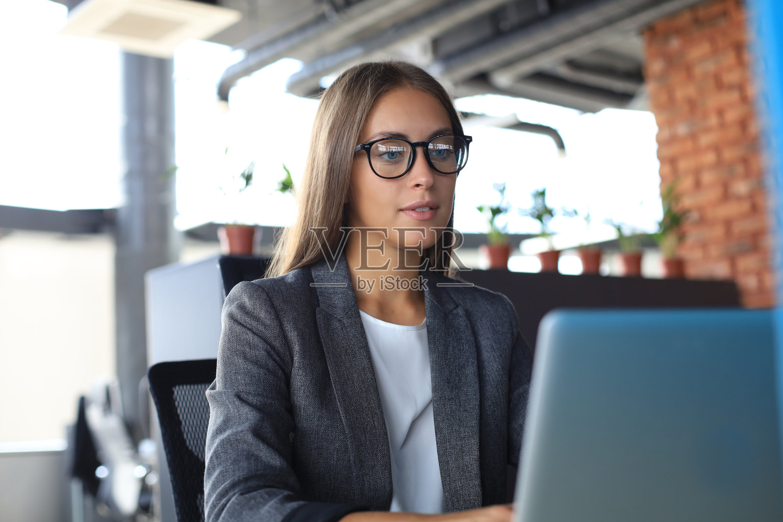 美丽的商务女性在办公室用笔记本电脑工作照片摄影图片