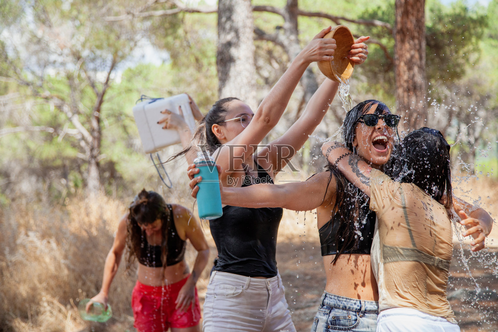 圣马丁瓦尔德伊格莱西亚斯，西班牙马德里。一群妇女在喷泉旁玩水降温。照片摄影图片