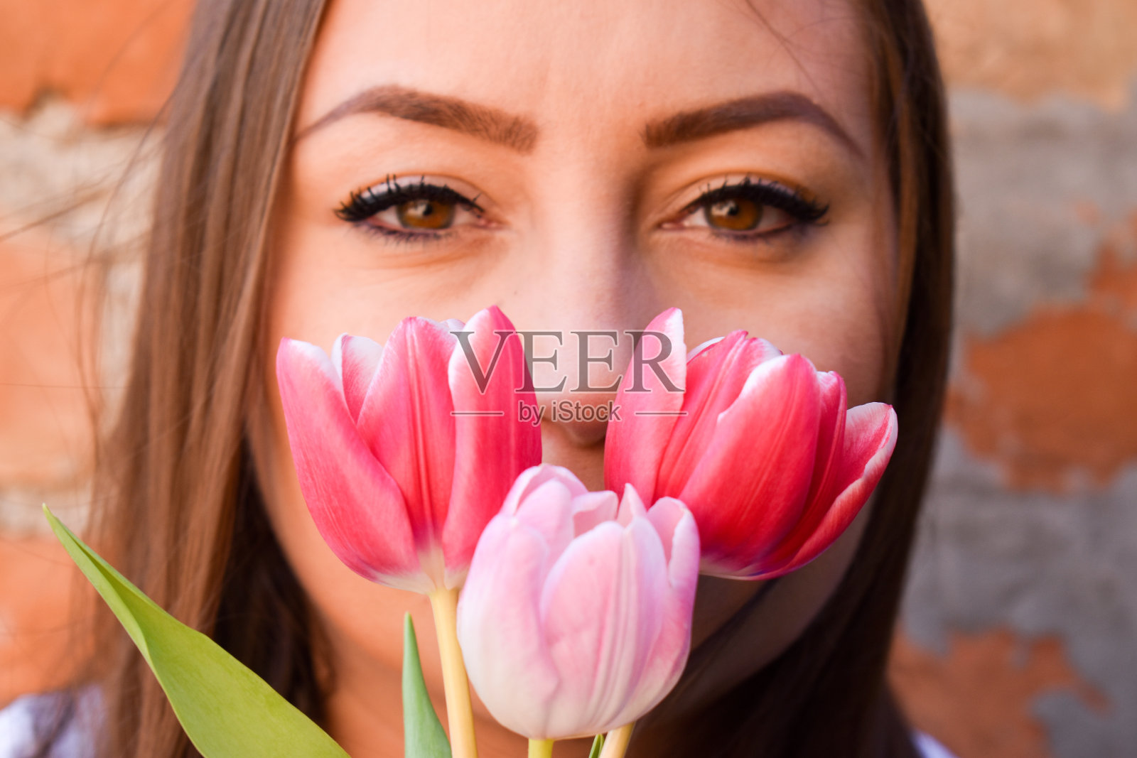 一个女人把三朵郁金香放在嘴唇前照片摄影图片