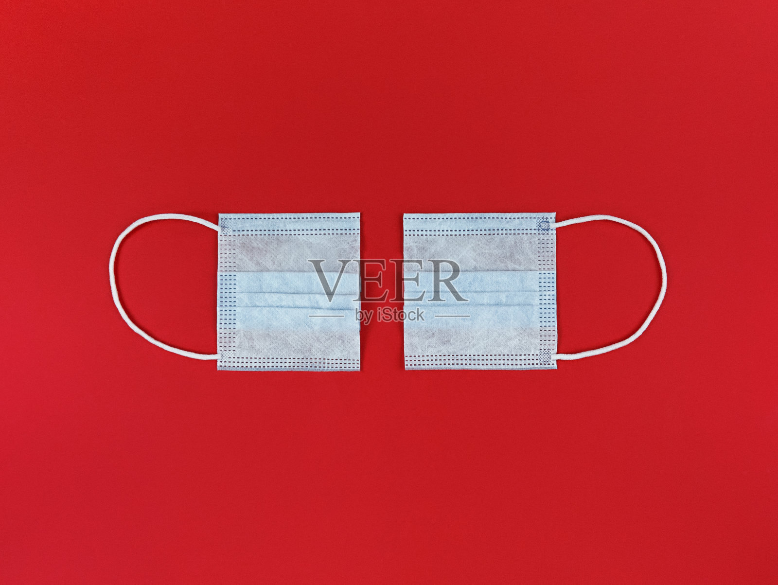医用一次性口罩在红色背景上切成两半。照片摄影图片