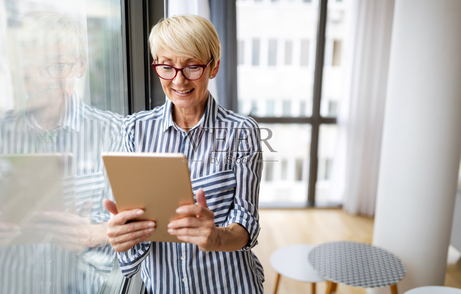 快乐的退休老年妇女在家放松，使用数字平板电脑。照片摄影图片
