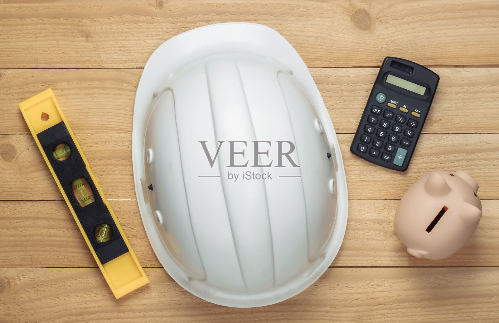 白色建筑安全帽，带有水平仪、储蓄罐和木制背景计算器。修理或建造房屋的费用前视图。照片摄影图片