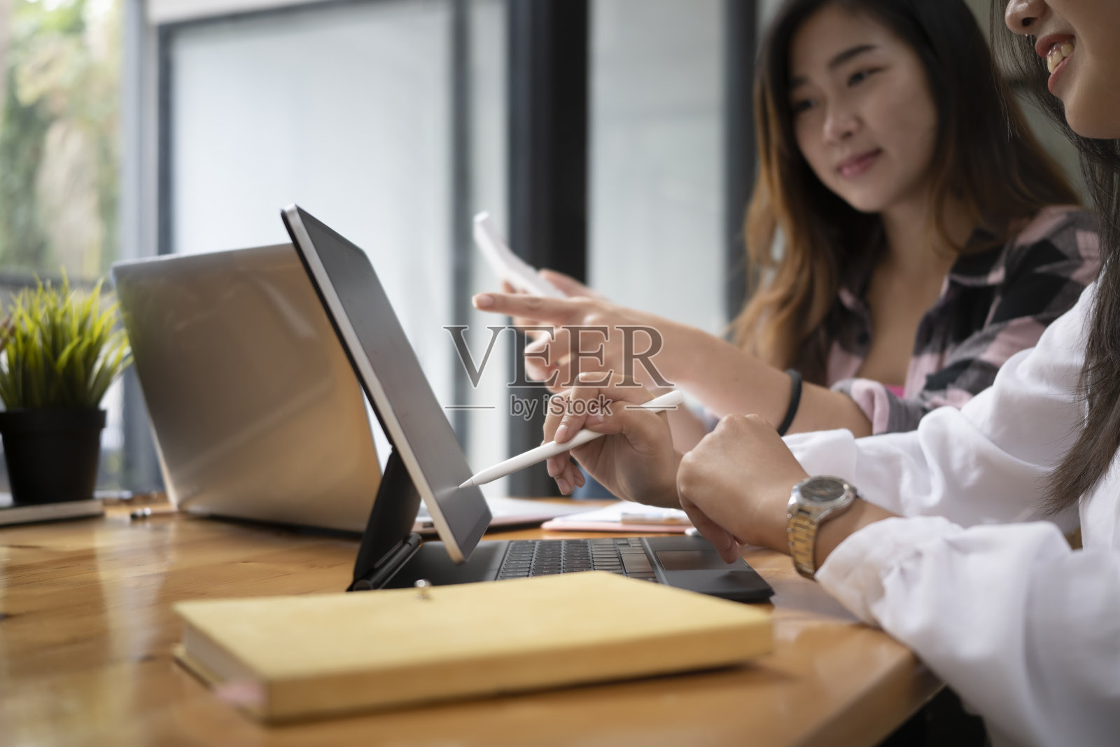 年轻的女性设计师在现代办公室工作，并讨论他们的项目平板电脑。照片摄影图片